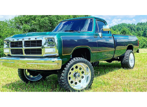Dodge pickup truck with custom paint job - green with navy accents and gold trim, custom tires/rims